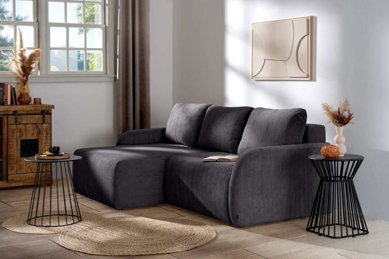 Z2 Ecksofa JENIFER Graues Ecksofa in einem modernen Wohnzimmer, seitliche Perspektive, mit dekorativen Kissen und Beistelltischen.