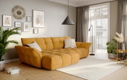 Mosterdgele, gecapitonneerde stoffen hoekbank met chaise longue in een lichte, moderne woonkamer met kussens, wanddecoratie en grote ramen; perspectief: schuin van voren links op bankhoogte