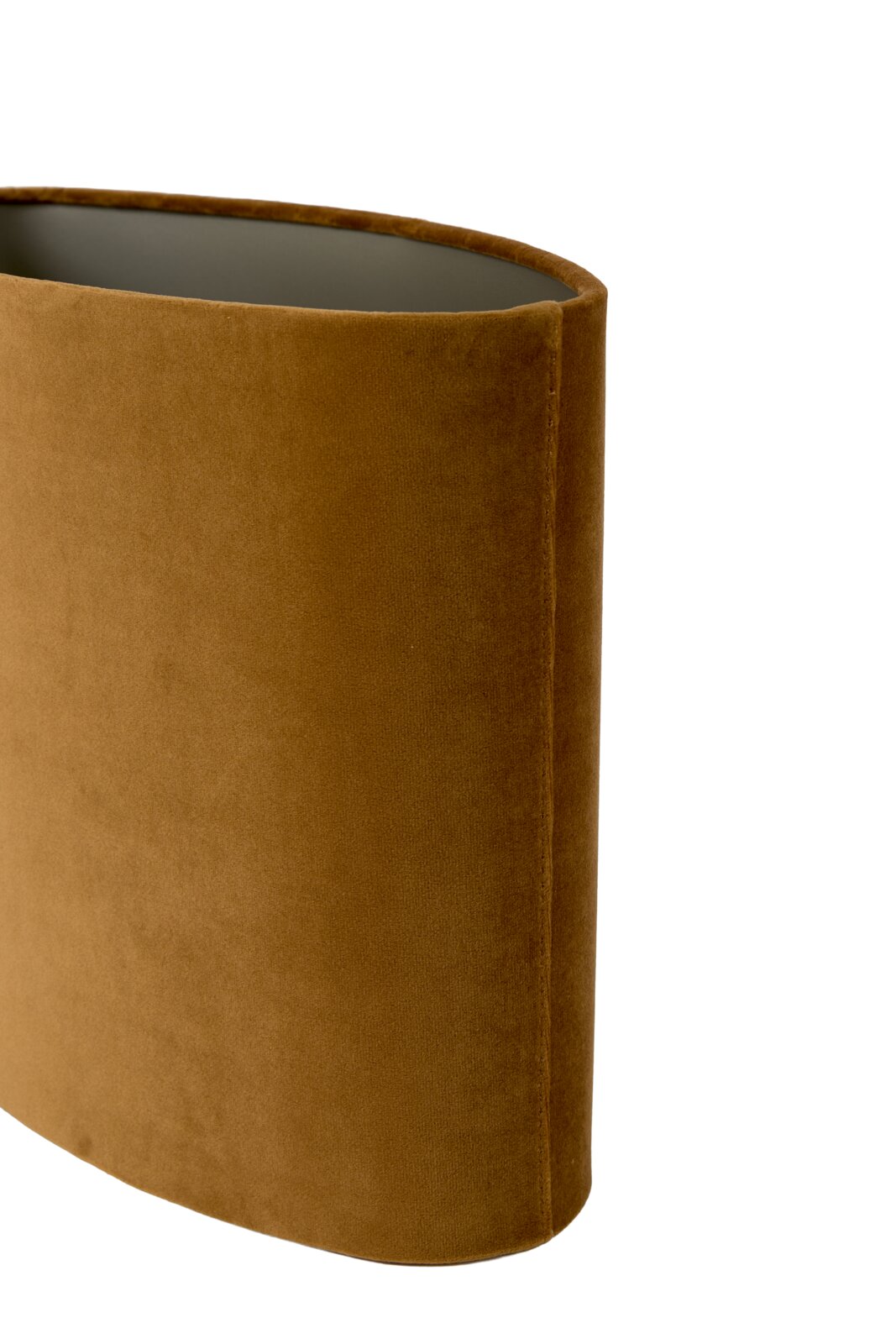Close-up in schuin bovenaanzicht van een ovale lampenkap, bekleed met warm okerbruin fluweel en afgewerkt met een subtiele stiknaad.