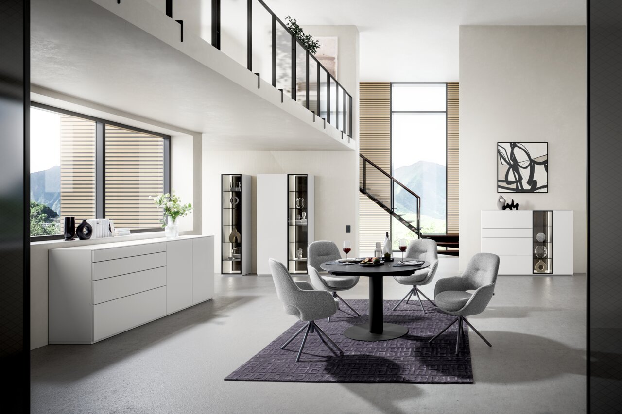 WK-Wohnen Highboardkombination 420 VIVA Moderne Wohnzimmereinrichtung mit Highboardkombination und Vitrinen in einem hellen Raum mit großen Fenstern und stilvollen Möbeln, seitliche Perspektive.