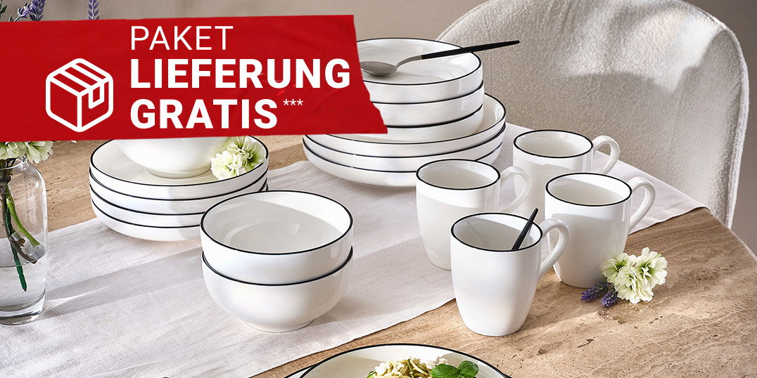 Weißes Geschirr mit schwarzem Rand auf gedecktem Esstisch, dekoriert mit Blumen und Besteck.