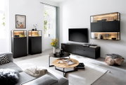 Modern ingerichte woonkamer met matzwarte tv-meubelset en wandvitrine met warme ledverlichting en houten accenten, gefotografeerd in een brede frontale hoek (schuin van voren)