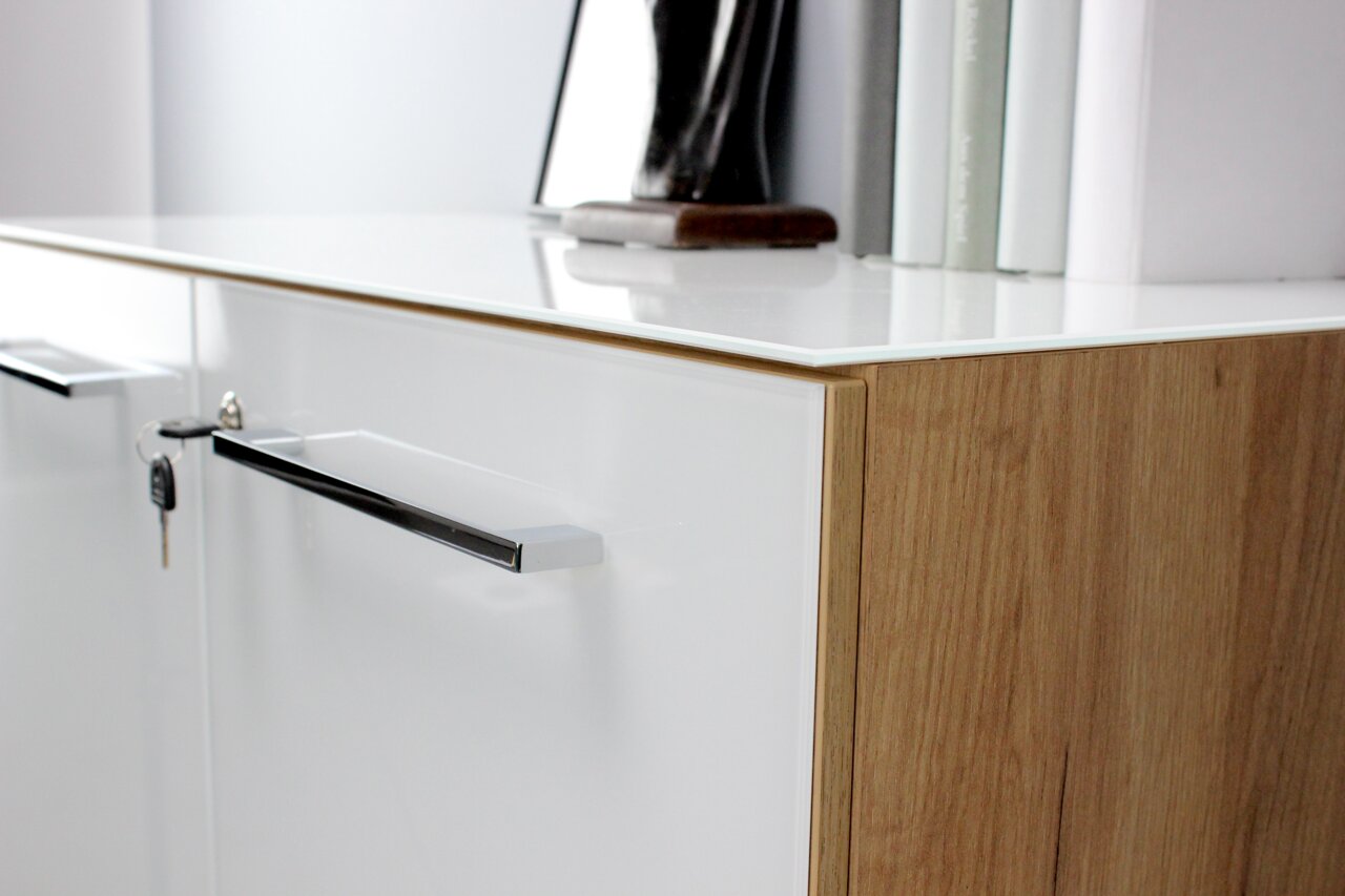 Nahaufnahme eines modernen Aktenschranks mit weißer Front und Holzseiten, seitliche Perspektive.