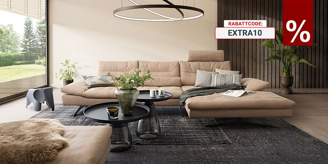 Modernes Wohnzimmer mit beigem Ecksofa, runden Couchtischen, Teppich und großer Pendelleuchte