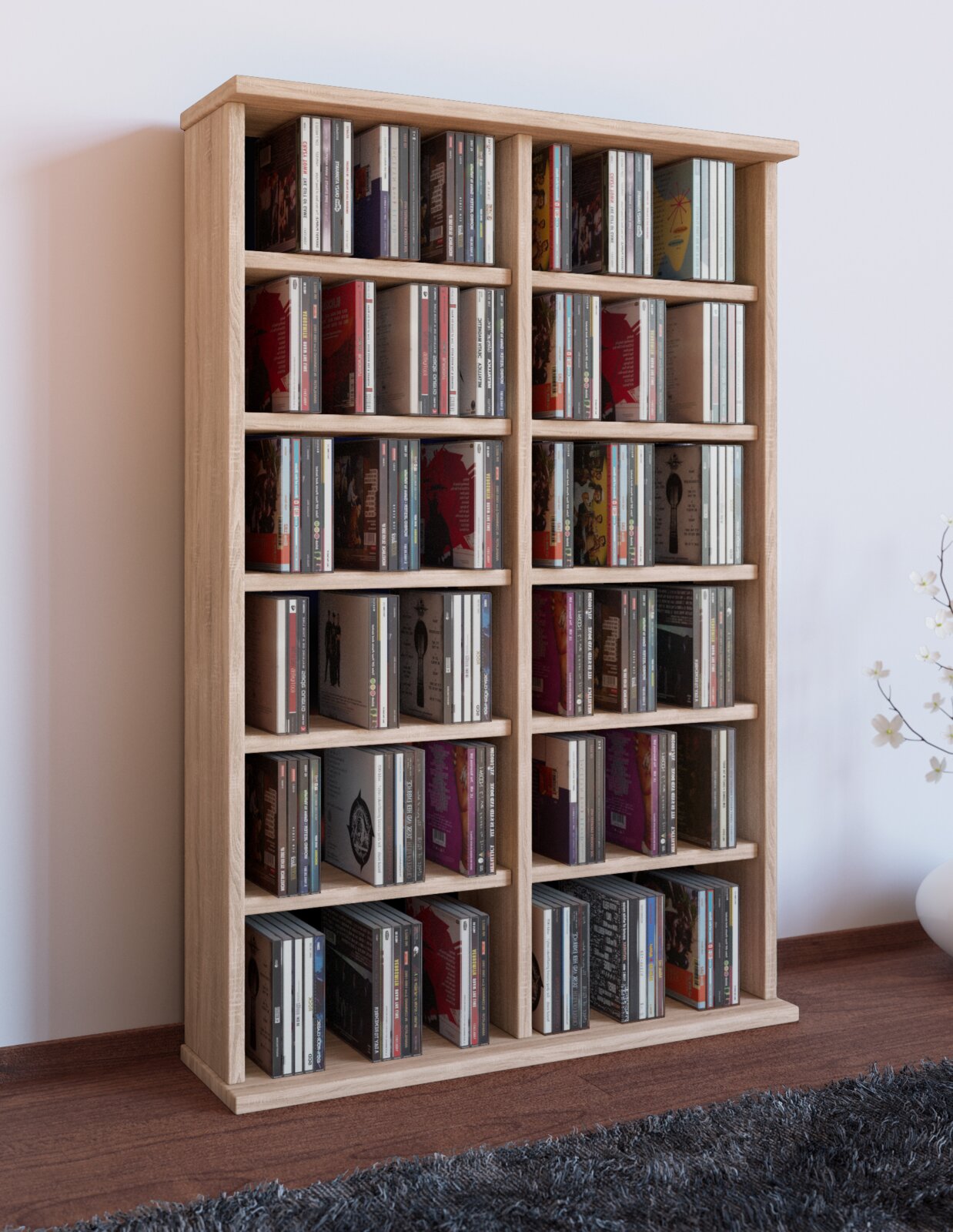 Hohes CD-Regal aus hellem Holz mit mehreren Fächern, gefüllt mit CDs, freistehend im Wohnraum; perspektivische Frontansicht leicht von links.