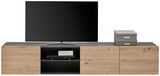 Frontansicht eines TV-Hängelowboards mit Holzoptik, einem Fernseher darauf und zwei grauen Boxen auf der rechten Seite.