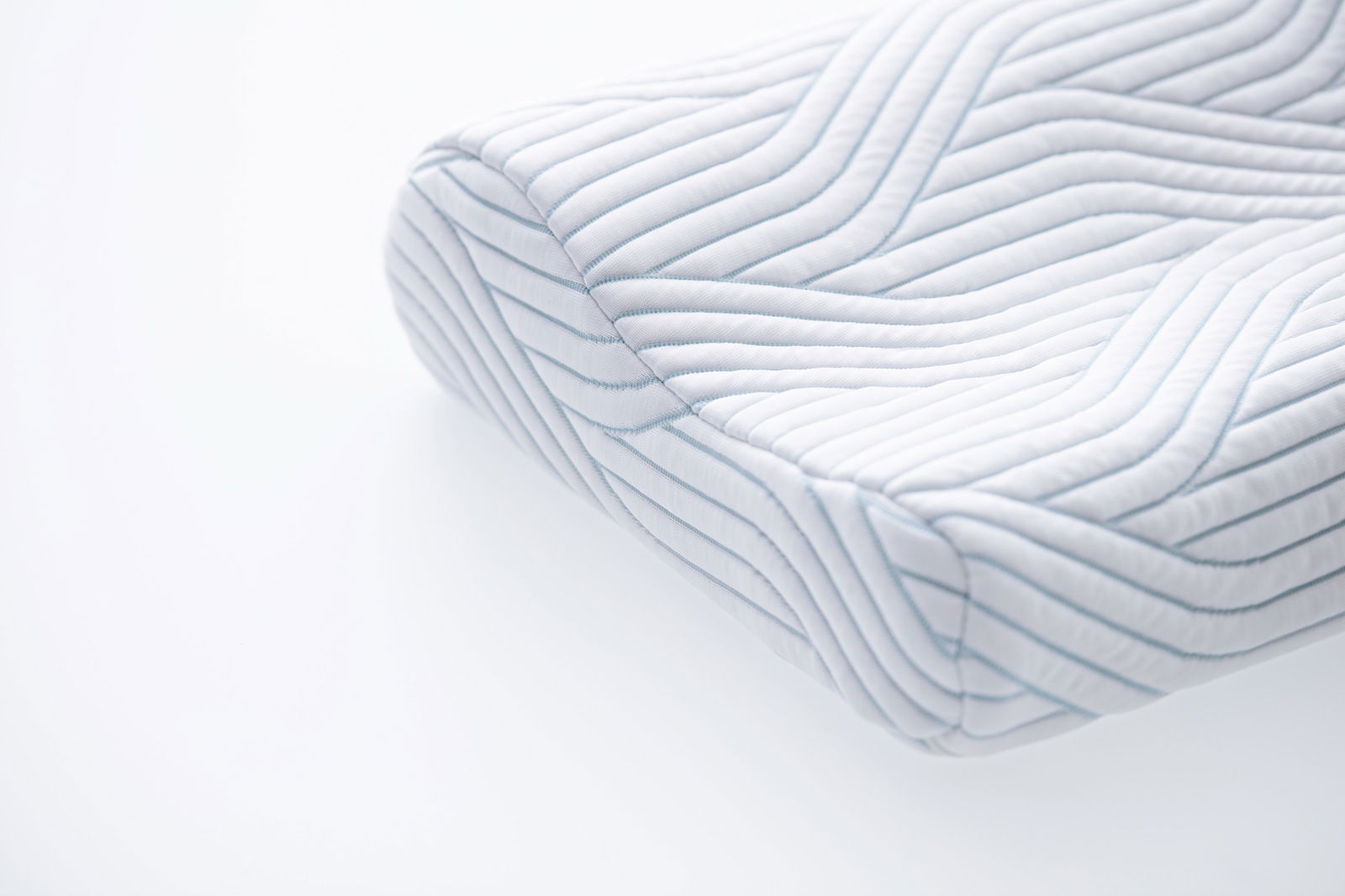 Nahaufnahme eines ergonomischen Schlafkissens mit gestepptem Muster, seitliche Perspektive