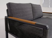 Nahaufnahme einer modernen, zweisitzigen Sitzbank mit grauen Polstern und Armlehnen aus Holz und Metall. Die Perspektive zeigt die rechte Seite der Bank.