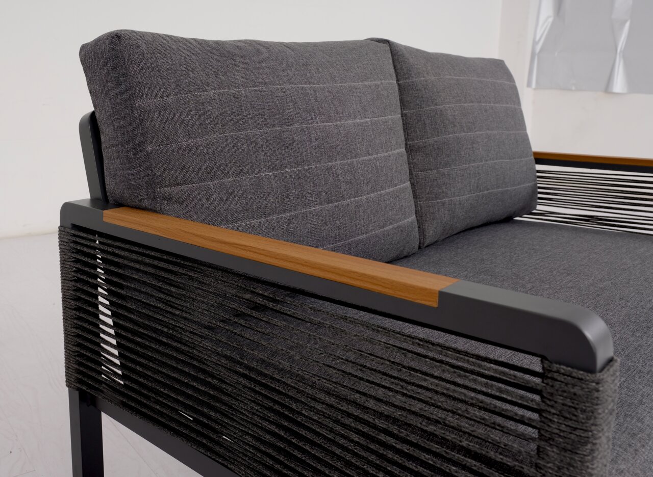 Nahaufnahme einer modernen, zweisitzigen Sitzbank mit grauen Polstern und Armlehnen aus Holz und Metall. Die Perspektive zeigt die rechte Seite der Bank.