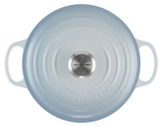 Runde, meerblaue Bräter von oben mit zwei Griffen und Edelstahlknauf, Le Creuset Logo sichtbar.