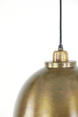 Nahaufnahme einer Hängeleuchte mit goldener, gebürsteter Oberfläche und schwarzem Kabel, von der Seite betrachtet.