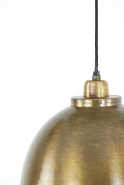 Nahaufnahme einer Hängeleuchte mit goldener, gebürsteter Oberfläche und schwarzem Kabel, von der Seite betrachtet.