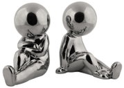 Zwei silberne, glänzende Buchstützen in Form von stilisierten, sitzenden Figuren. Die Figuren sind aus einer frontalen Perspektive zu sehen.