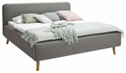 Graues Polsterbett mit Holzbeinen, dekoriert mit mehreren Kissen und einer Decke, seitliche Perspektive
