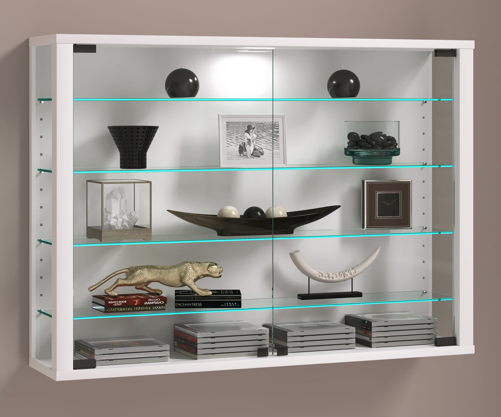 Weiße Wandvitrine mit Glasschiebetüren und mehreren Glasböden, dekoriert mit Vasen, Bilderrahmen, Schale und Büchern Frontalansicht.