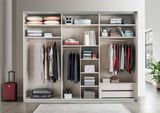Offener Schwebetürenschrank mit zwei Türen, gefüllt mit Kleidung, Kissen und Accessoires, aus der Frontalperspektive fotografiert.