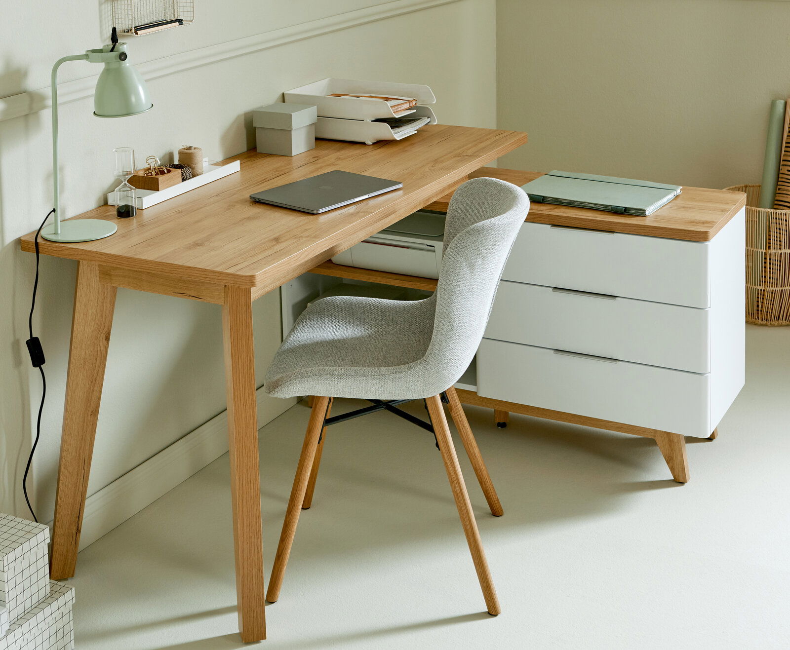 Moderner Eck-Schreibtisch aus Holz mit weißem Rollcontainer und grauem Stuhl, seitliche Perspektive