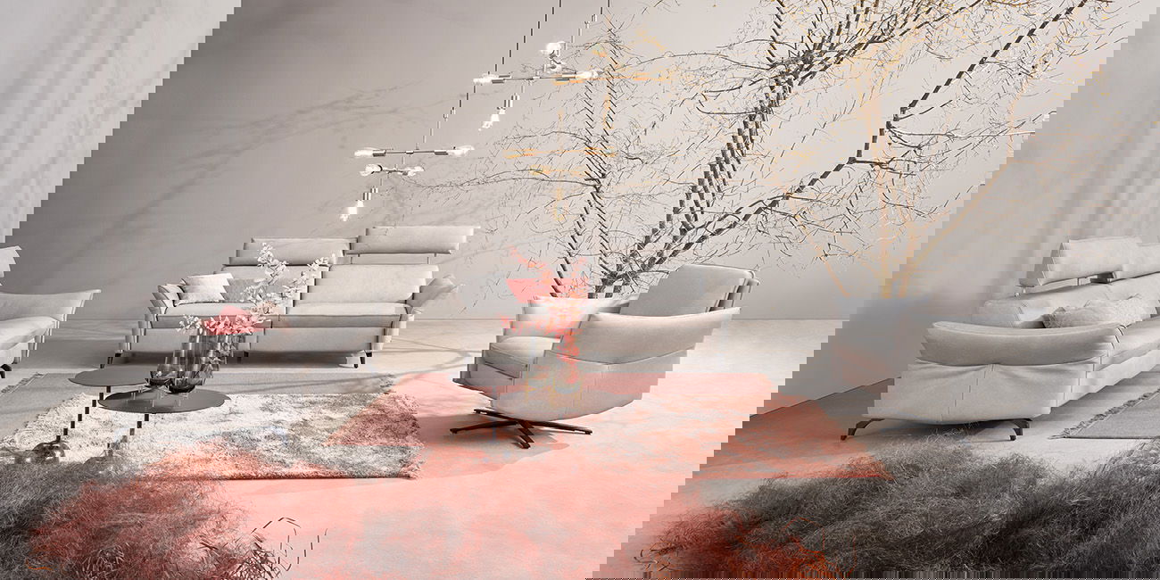 ein Wohnzimmer in hellen rosa, grau und weiß Tönen mit einer hellen Sitzgarnitur.