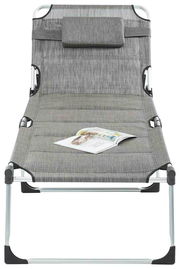 Graue Liege mit Kopfstütze und Magazin, frontal fotografiert.