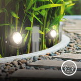 Erdspieß Spot Verlängerungsset im Garten, seitliche Perspektive, beleuchtet Pflanzen und Gehweg.