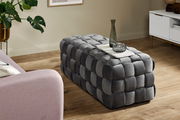 Grauer, gepolsterter Hocker in rechteckiger Form mit geflochtenem Design, seitliche Perspektive.
