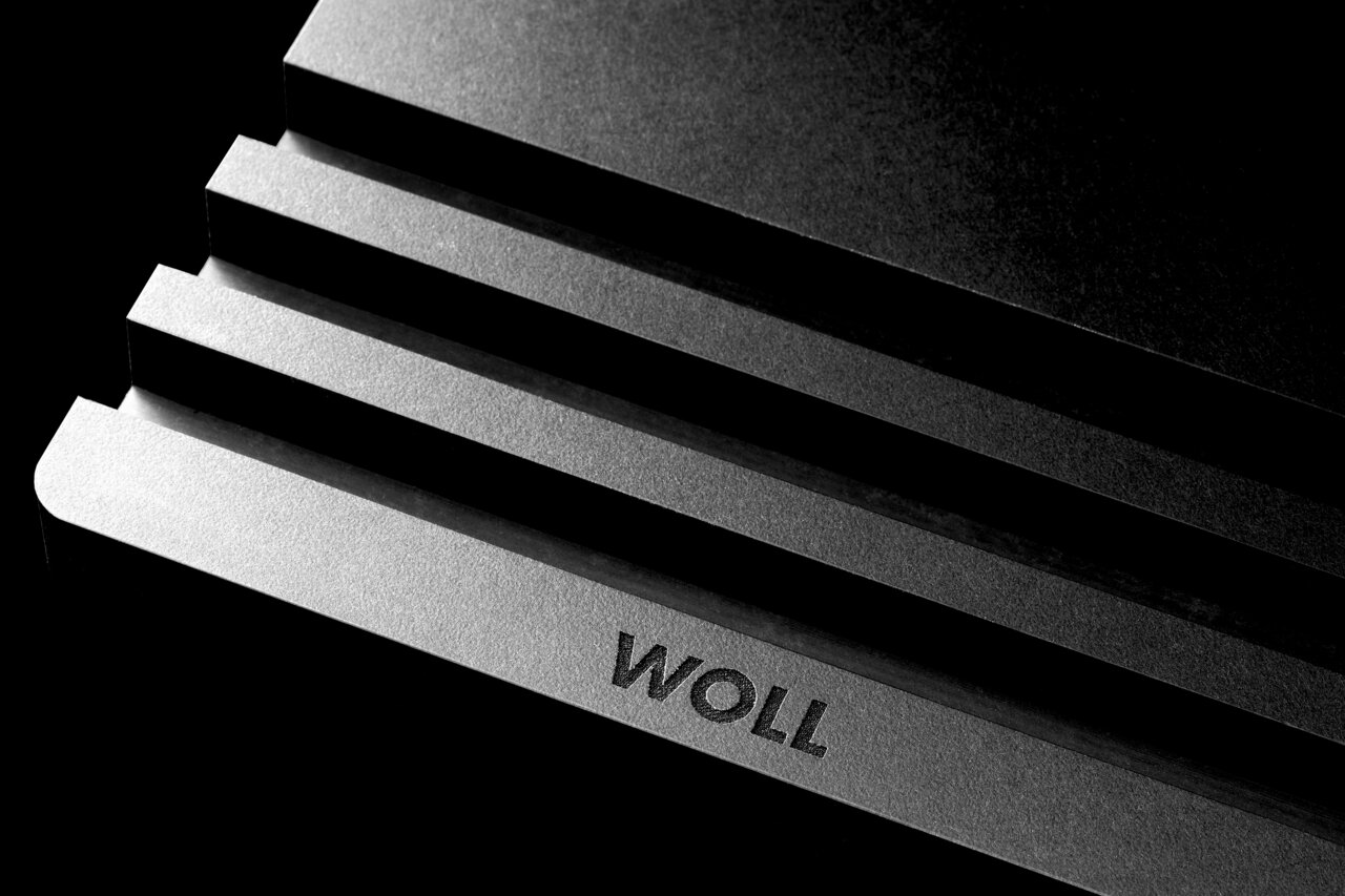 Close-up van een gestapelde snijplankhouder met het opschrift 'WOLL' in een diagonaal perspectief.