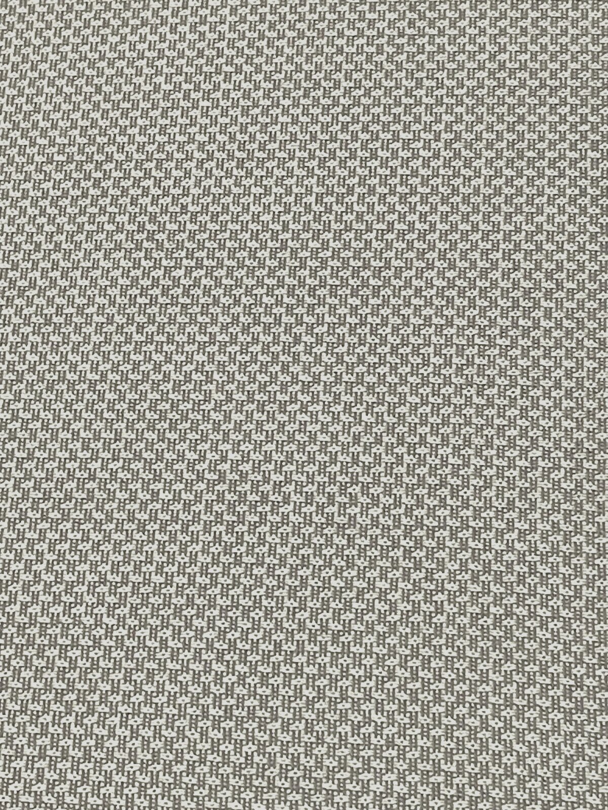 Nahaufnahme eines Stoffmusters in Grau und Weiß mit kleinem geometrischem Design, von oben betrachtet.