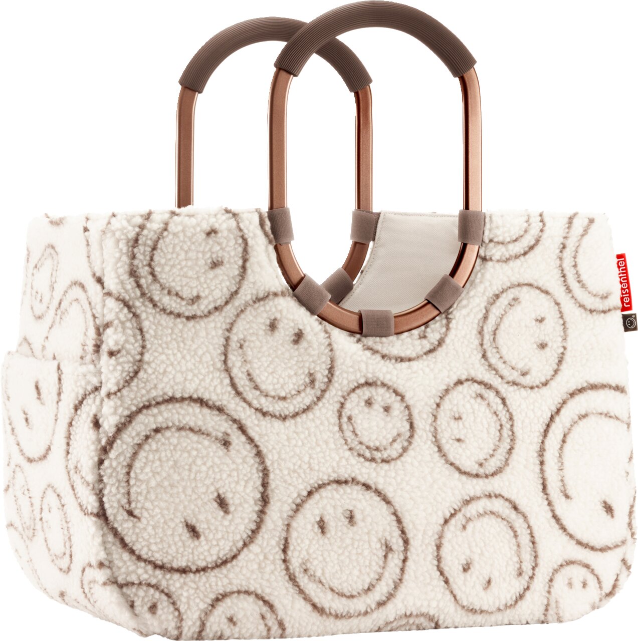 Flauschige Handtasche aus Teddyplüsch in Creme mit Smiley-Muster, zwei ovalen braunen Tragegriffen und kleinem roten Reisenthel-Label, Frontansicht leicht schräg von vorn.