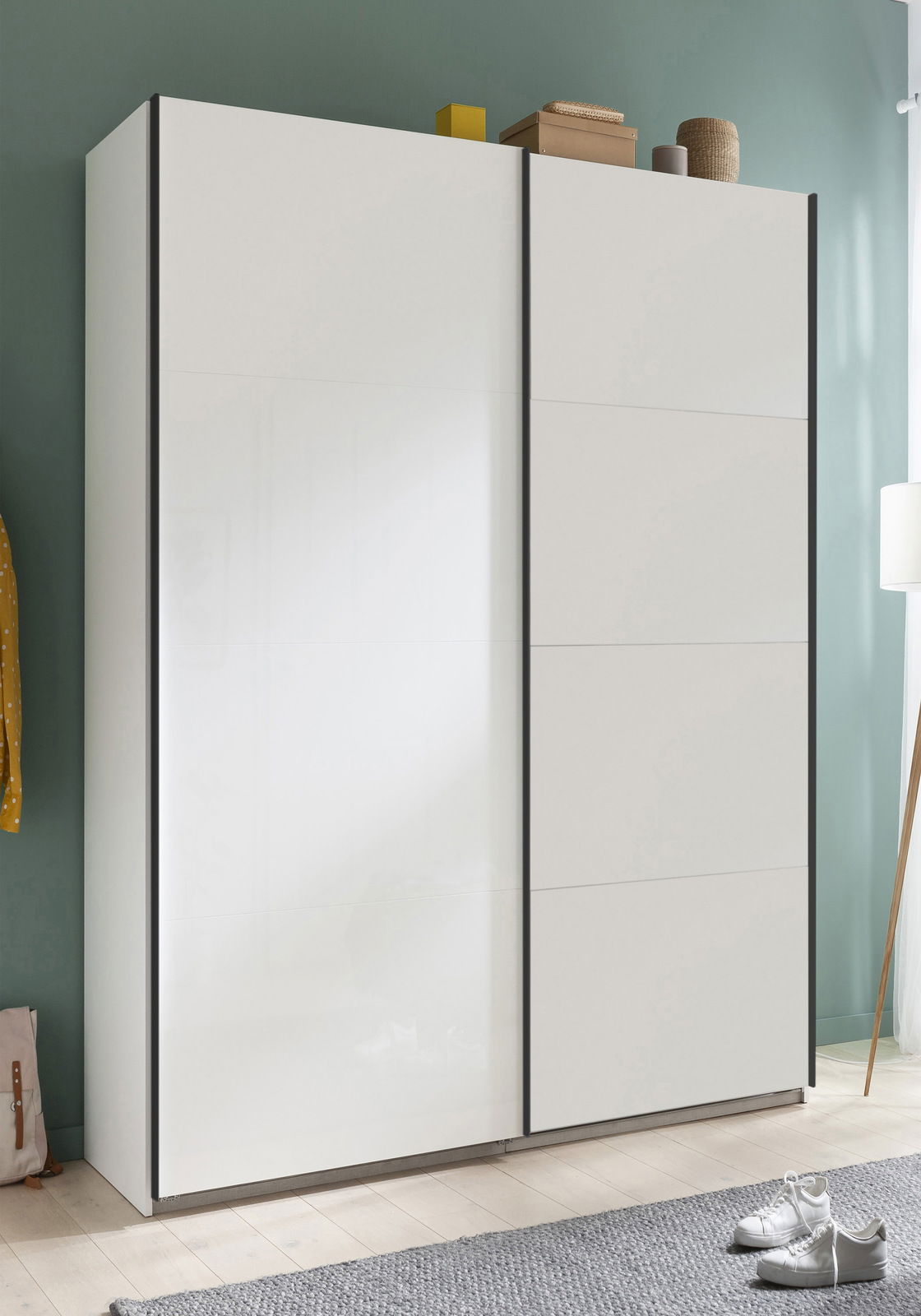 Moderner weißer Schwebetürenschrank mit zwei Türen, frontal fotografiert, in einem stilvoll eingerichteten Raum.