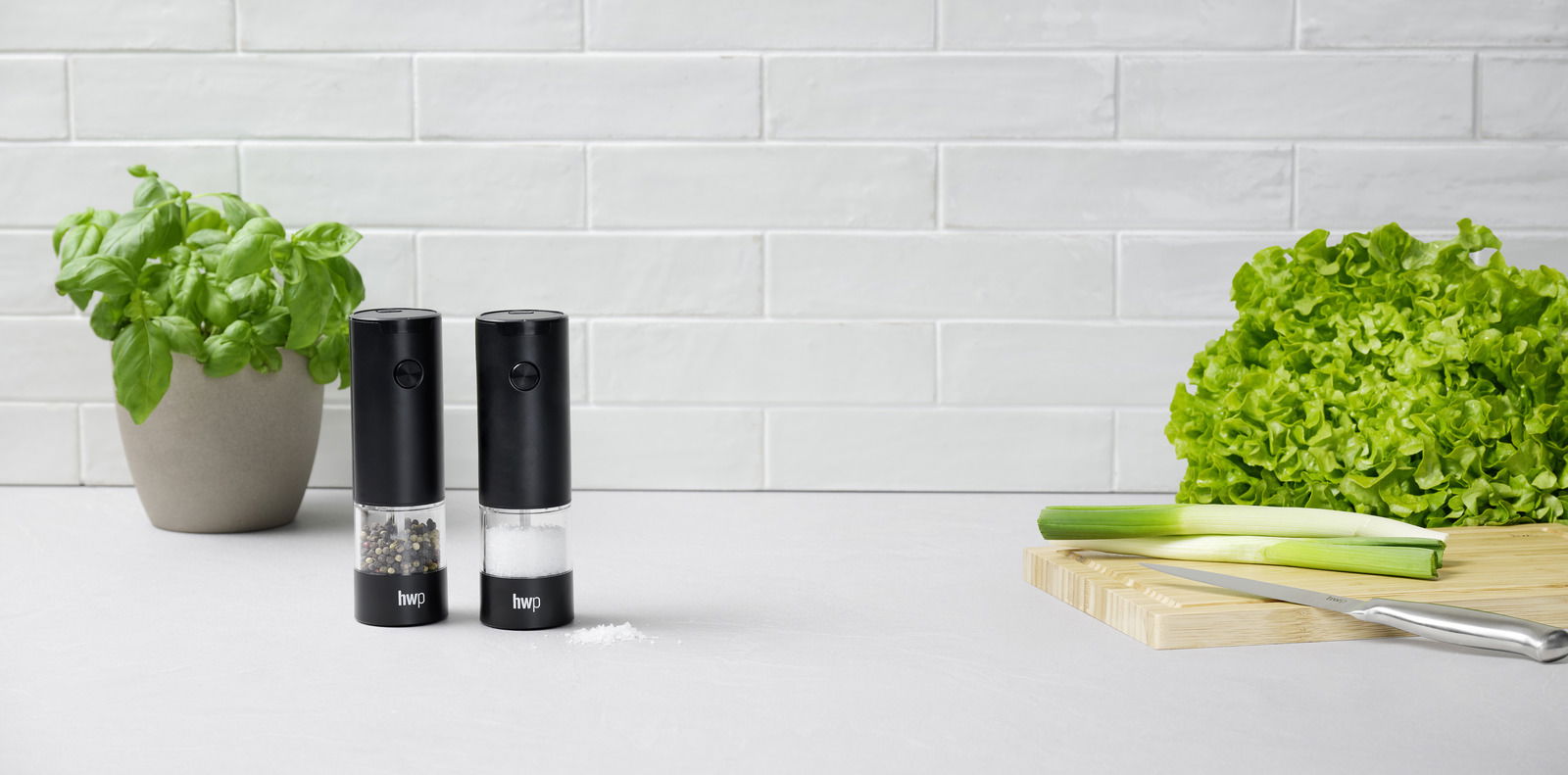 Homeware Salz-/Pfeffermühlen-Set. 2-tlg Salz- und Pfeffermühlen-Set, 2-teilig, in moderner Küche mit frischen Kräutern und Gemüse, seitliche Perspektive
