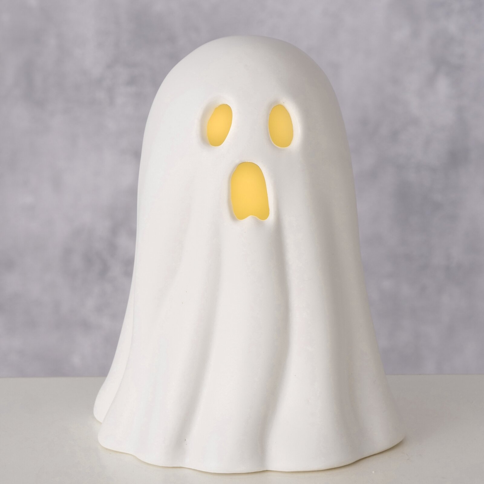 Weiße Geisterfigur mit leuchtenden Augen und Mund, frontal betrachtet.