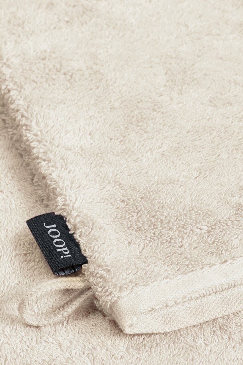 JOOP! Waschhandschuh Nahaufnahme eines beigen Waschhandschuhs mit einem schwarzen Joop!-Etikett.