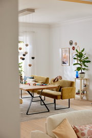 Gemütliche Esszimmerbank in senfgelber Farbe mit Armlehnen, seitliche Perspektive, in einem modern eingerichteten Raum mit Holztisch und Dekorationen.