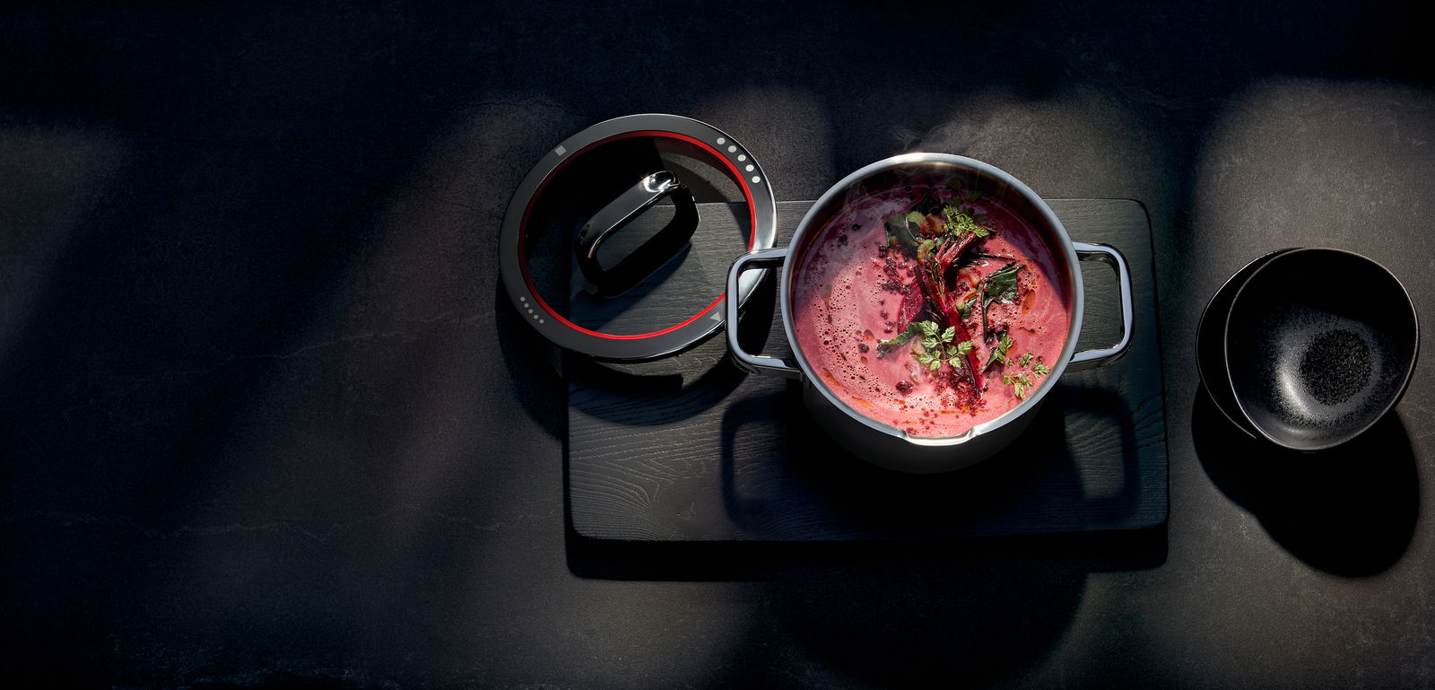 Bratentopf mit Deckel, gefüllt mit roter Suppe und Kräutern, aus der Vogelperspektive