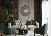 Grote, decoratieve wandklok met Romeinse cijfers en tandwielen, aan de muur in de woonkamer boven een bank bevestigd.