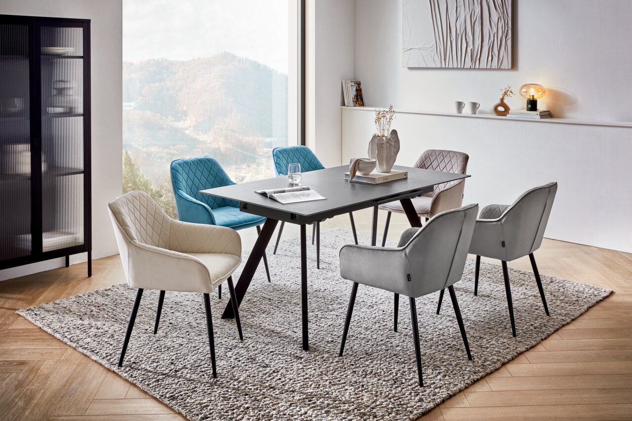 Novel Esstisch PLANET Moderner Esstisch mit schwarzer Tischplatte und sechs gepolsterten Stühlen in verschiedenen Farben, in einem stilvoll eingerichteten Raum mit großem Fenster und Bergblick, aus seitlicher Perspektive.