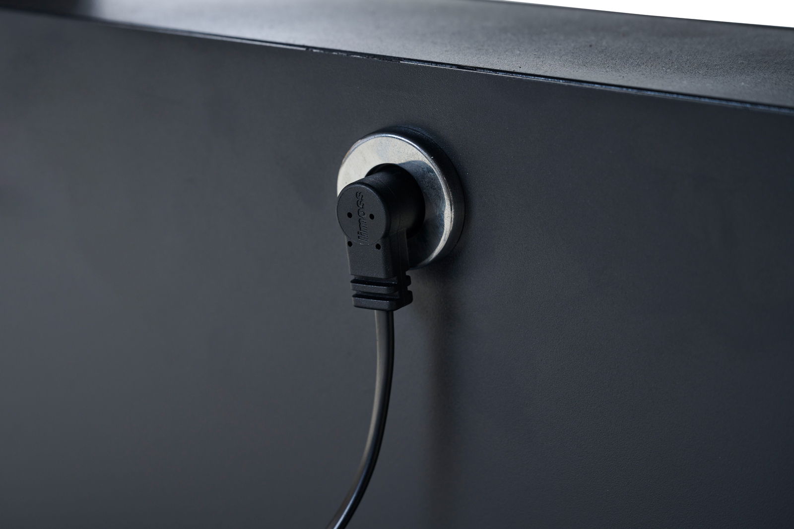 Nahaufnahme eines schwarzen Kabels, das in eine Steckdose an einem Garten E-Lifttisch eingesteckt ist, seitliche Perspektive.