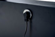 Nahaufnahme eines schwarzen Kabels, das in eine Steckdose an einem Garten E-Lifttisch eingesteckt ist, seitliche Perspektive.