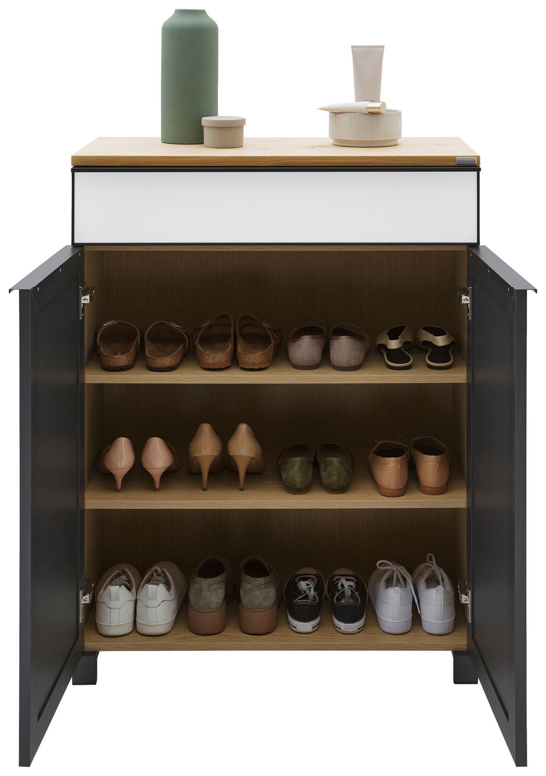 Moderner Schuhschrank mit offenen Türen, gefüllt mit verschiedenen Schuhen auf drei Regalböden, aus der Frontalperspektive fotografiert. Obenauf stehen dekorative Gegenstände.