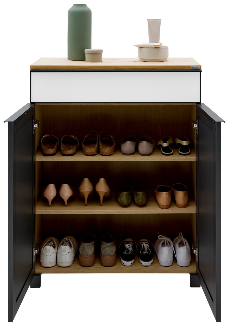 Moderner Schuhschrank mit offenen Türen, gefüllt mit verschiedenen Schuhen auf drei Regalböden, aus der Frontalperspektive fotografiert. Obenauf stehen dekorative Gegenstände.
