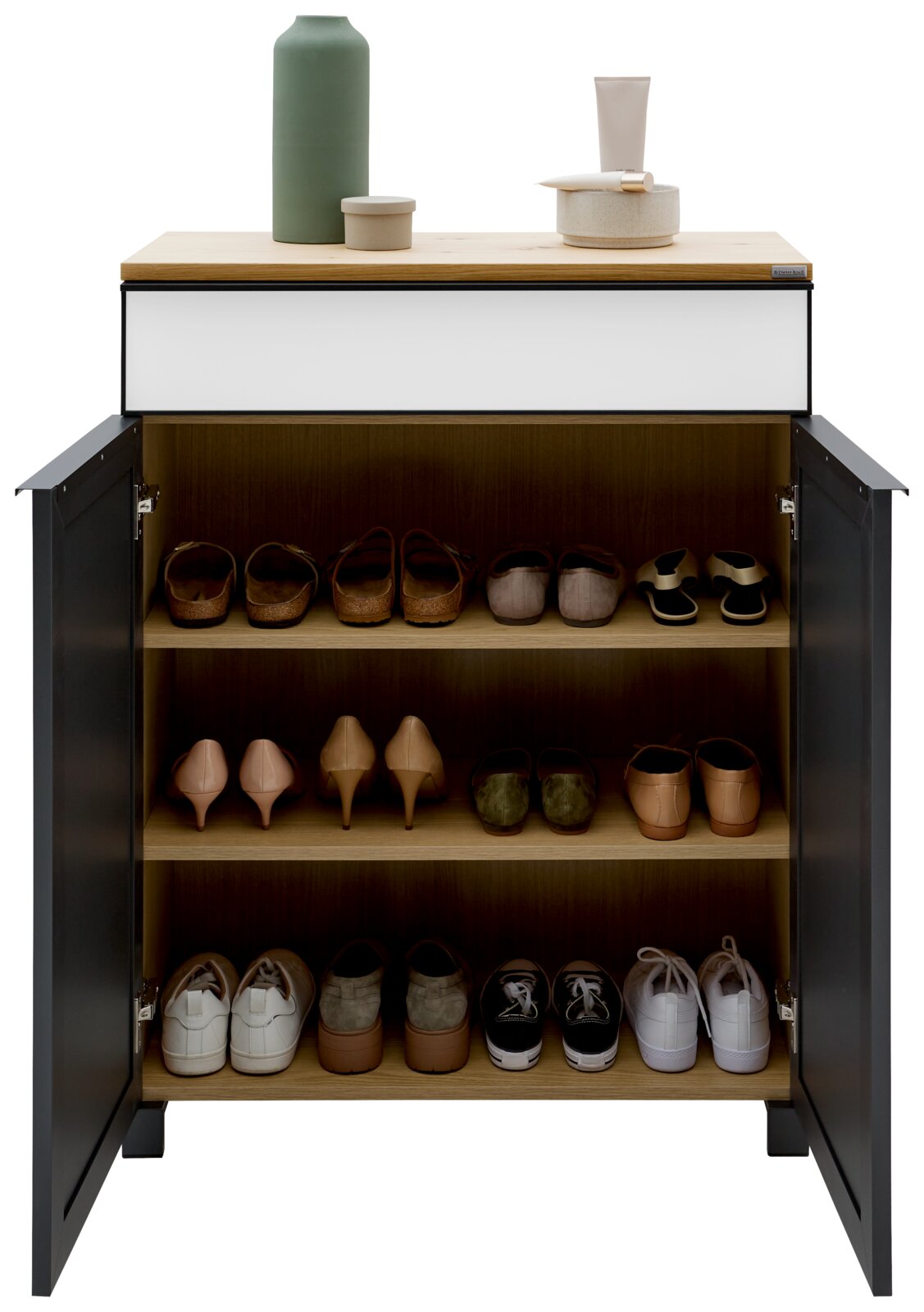 Moderne schoenenkast met open deuren, gevuld met verschillende schoenen op drie planken, gefotografeerd vanuit een vooraanzicht. Bovenop staan decoratieve voorwerpen.