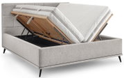Gepolstertes graues Boxspringbett mit geöffnetem Stauraum und hochklappbarem Lattenrost, Matratzen angehoben; Ansicht schräg von vorne.