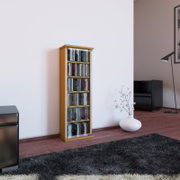 Schmaler CD-/DVD-Turm aus Holz mit transparenten Frontscheiben, gefüllt mit Medien, im Wohnzimmer an einer weißen Wand; Perspektive: leicht seitliche Frontansicht auf Augenhöhe.