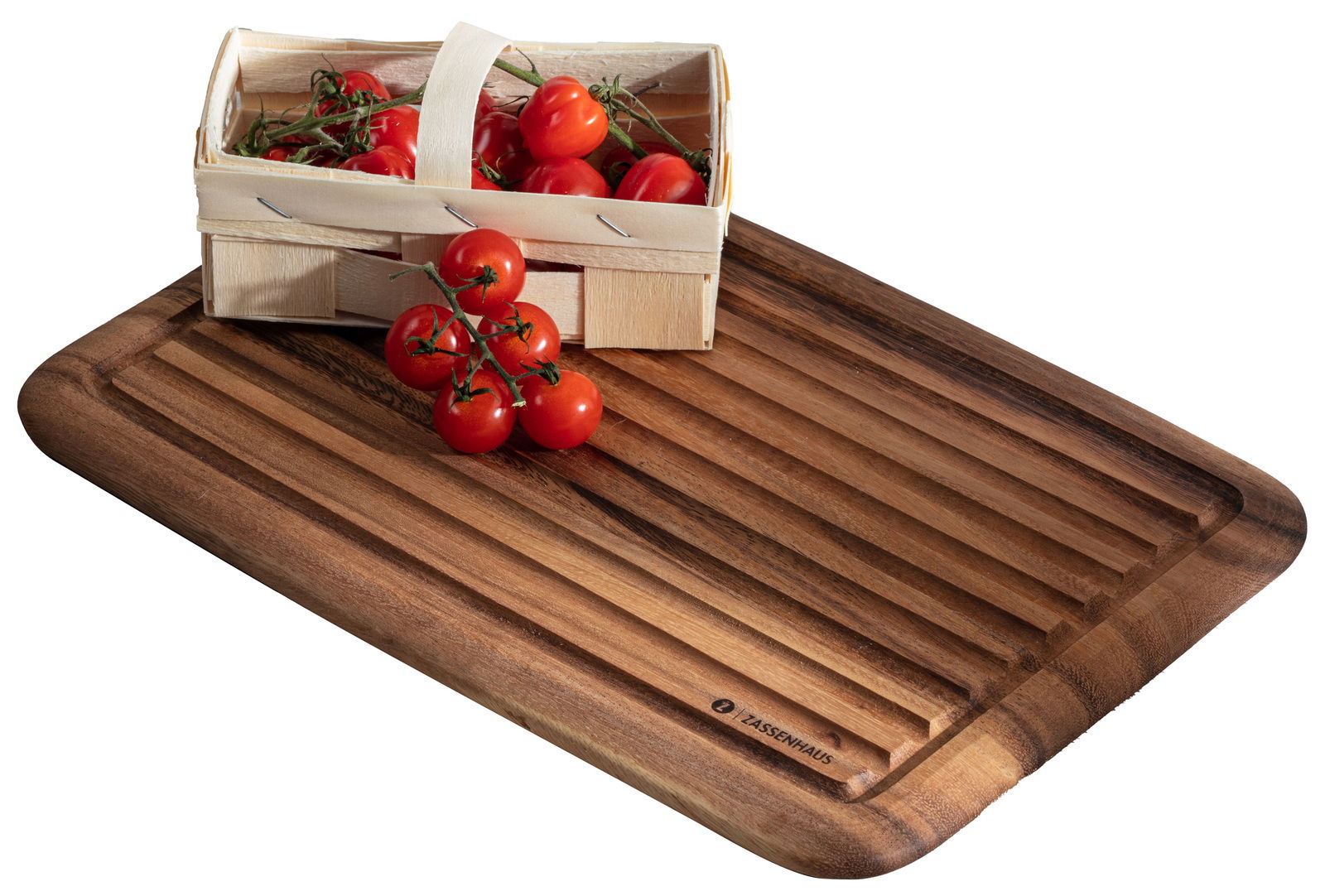 Brotschneidbrett aus Akazienholz mit Rillen, darauf ein kleiner Korb mit frischen Tomaten, Perspektive von oben.