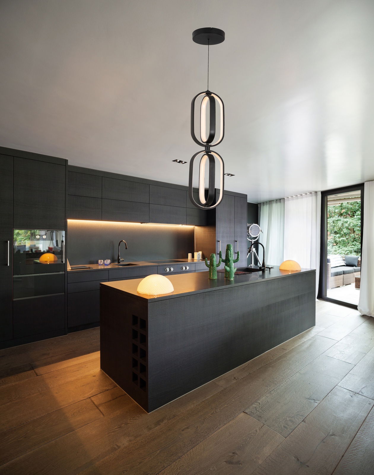 Moderne LED-Hängeleuchte in einer stilvollen, dunklen Küche, von unten betrachtet.