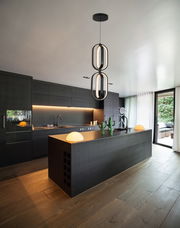 Moderne LED-Hängeleuchte in einer stilvollen, dunklen Küche, von unten betrachtet.