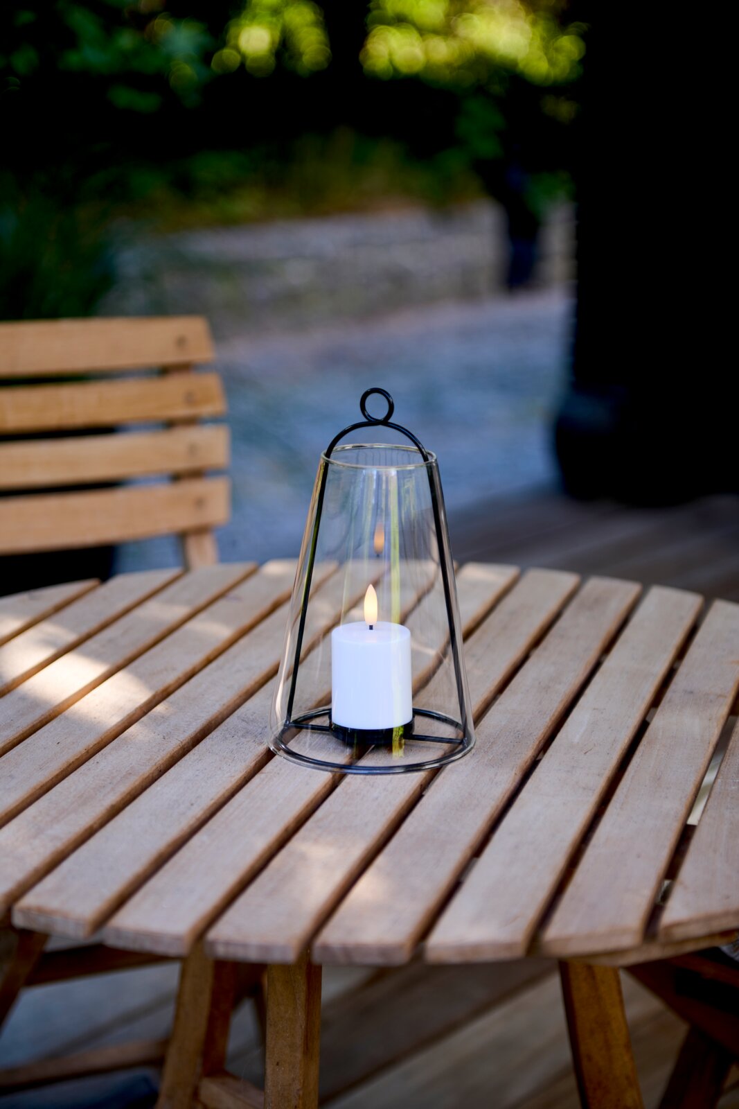 Lantaarn met led-kaars op een houten tafel in de buitenlucht, zijaanzicht