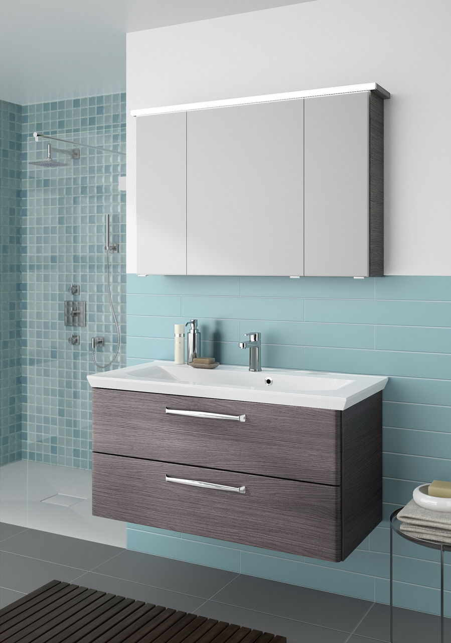 Moderner Badblock mit Waschbecken und Unterschrank in Holzoptik, frontal betrachtet, vor einer Wand mit blauen Fliesen.