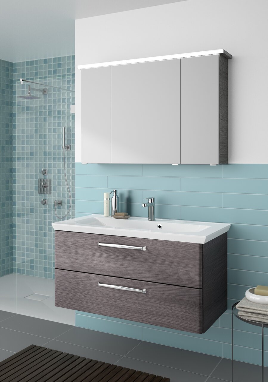 Moderner Badblock mit Waschbecken und Unterschrank in Holzoptik, frontal betrachtet, vor einer Wand mit blauen Fliesen.