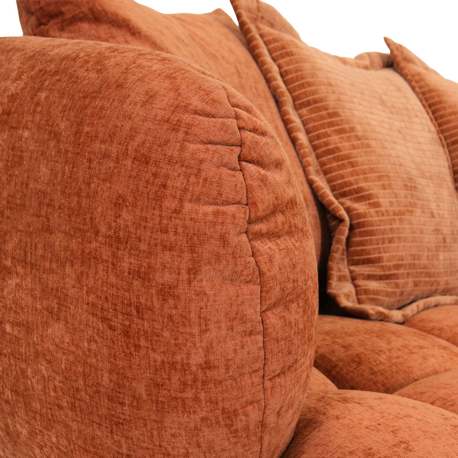 Nahaufnahme eines Big-Sofas in warmem Terrakotta-Ton mit weichen, strukturierten Kissen, seitliche Perspektive.